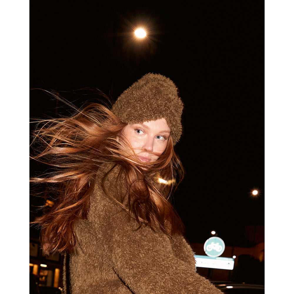 Inspiratiefoto bij Lana Grossa Pelliccia 016 Bordeaux: vrouw met bruine turbanmuts in een sfeervolle avondomgeving - Lana Grossa Pelliccia 001 Crème