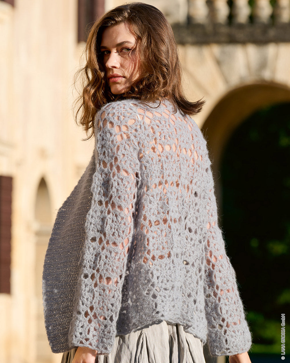 Lana Grossa Setasuri 062 Umbra - model draagt een gebreide cardigan met een zachte soepele valling - sfeerfoto 17 - Lana Grossa Setasuri 068 Framboos
